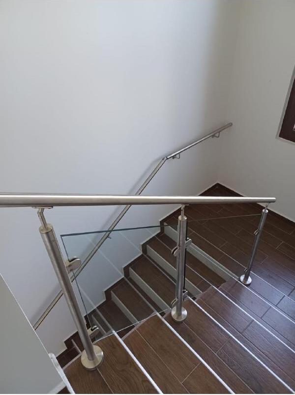 Barandal de vidrio templado con pasamanos de acero inoxidable en escalera de residencia en San Pedro Sula