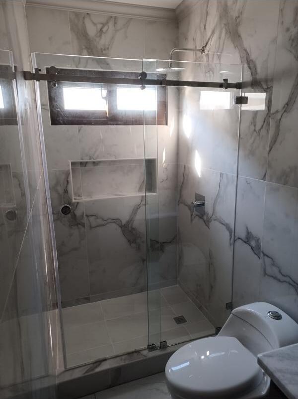Puerta de baño de vidrio templado abatible con herrajes en residencia de Honduras